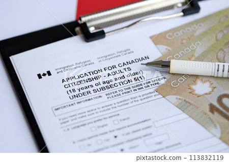 Application for Canadian citizenship for adults on table with pen and dollar bills close up 113832119
