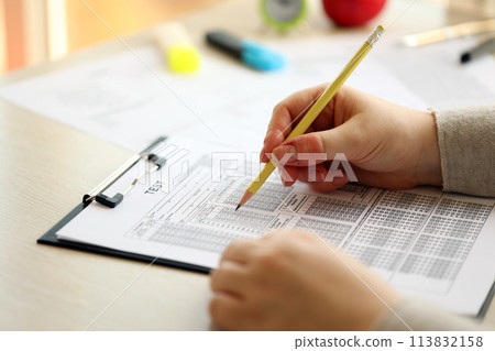 Female student hands testing in exercise and taking fill in exam paper sheet with pencil at school test room, education concept Female student hands testing in exercise and taking fill in exam paper sheet with pencil at school test room, education concept 113832158