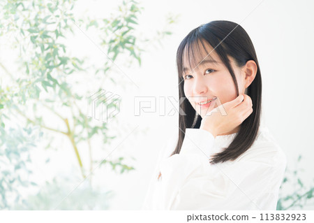 A young woman with a natural, refreshing green image brushing her hair back. Beauty image. Hair care and skin care image. A young woman with a natural, refreshing green image brushing her hair back. Beauty image. Hair care and skin care image. 113832923