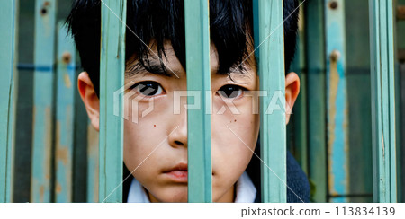 一個男孩透過柵欄看起來悲傷 113834139