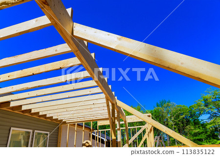An unfinished interior of newly built house with wooden framing supports beams stud timber framing 113835122