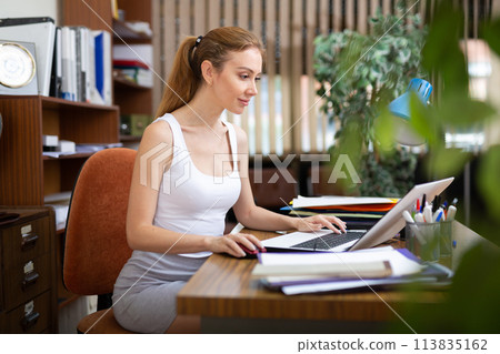 Smiling young business woman working at office desk Smiling young business woman working at office desk 113835162