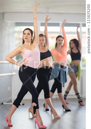 Female dancer practicing jazz-funk dance moves in high heels in studio Female dancer practicing jazz-funk dance moves in high heels in studio 113835200