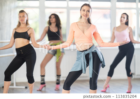 During lesson, girl learn to move and perform dance in heels with women companions During lesson, girl learn to move and perform dance in heels with women companions 113835204
