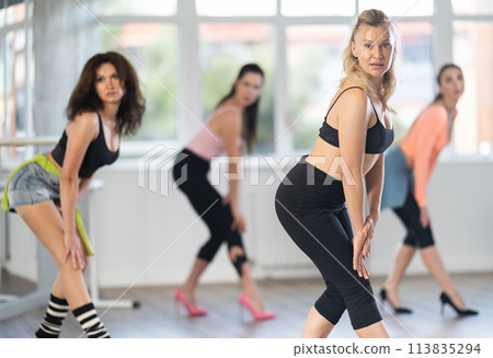 During lesson, woman learn to move and perform dance in heels with women companions During lesson, woman learn to move and perform dance in heels with women companions 113835294