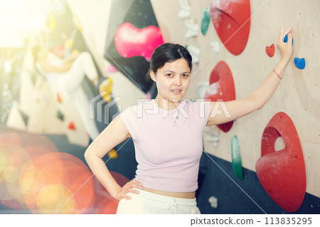 Young asian woman posing against climbing wall Young asian woman posing against climbing wall 113835295