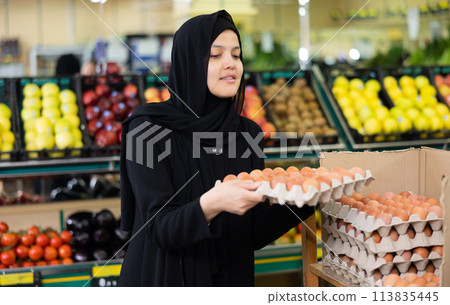 Asian girl in hijab buys chicken eggs in supermarket 113835445