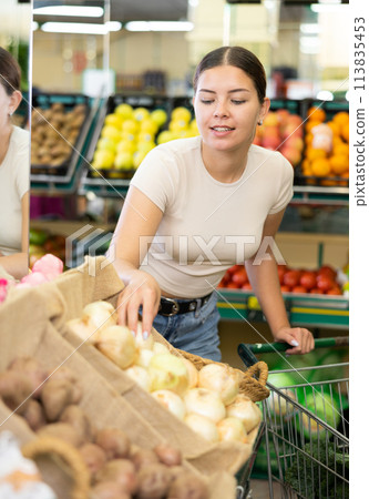 Portrait of female customer selecting onion in supermarket 113835453