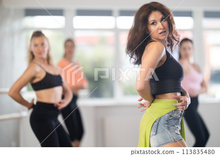 During lesson, woman learn to move and perform dance in heels with women companions 113835480
