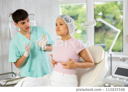 Young male doctor consulting female client on breast augmentation 113835586