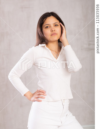 Dark-haired model put one hand on waist and coquettishly holds unfastened hair with handbreadth. Dark-haired model put one hand on waist and coquettishly holds unfastened hair with handbreadth. 113835936
