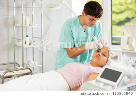 Young male cosmetologist doing whitening procedure to young woman Young male cosmetologist doing whitening procedure to young woman 113835940