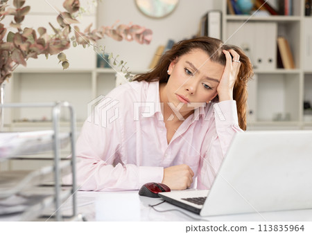 Exhausted female office worker sitting at her desk 113835964