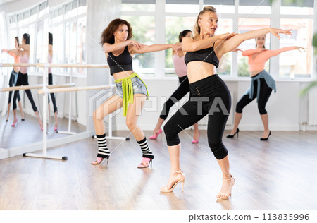 Confident woman leading group heels dance class in studio 113835996