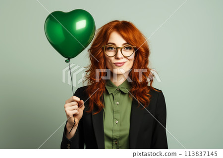 Attractive redhead woman with green heart-shaped balloon 113837145