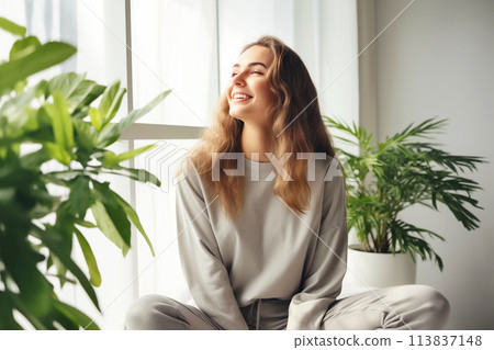 Happy young woman with a smile meditates among indoor plants at home. Mental health, Home gardening 113837148