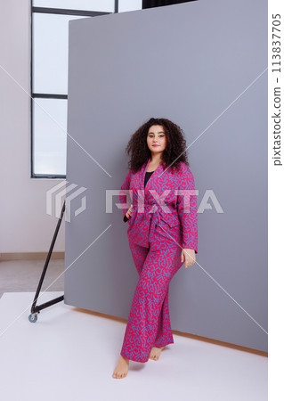 A woman is sitting on a wooden chair in a room with white walls A woman is sitting on a wooden chair in a room with white walls 113837705