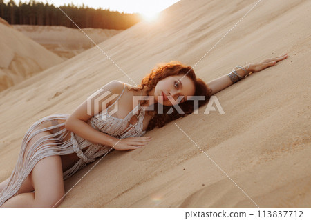 Sexy woman in a rope dress poses on a sandy hillside. Sexy woman in a rope dress poses on a sandy hillside. 113837712