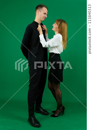 Young attractive business people in formal wear looking at each other. On a green background In a studio. Photo Young attractive business people in formal wear looking at each other. On a green background In a studio. Photo 113840313