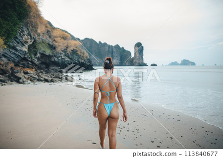 Woman in bikini walking on the beach 113840677
