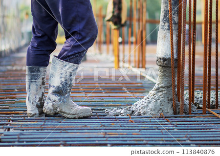Concrete is poured into a steel reinforcement frame at a construction site. 113840876