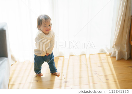 Little girl walking around the sofa 113841525