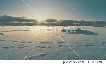 Sunrise Above Arctic Snow Covered Surface Top View. Sunset in Antarctica Winter Sunset Landscape with Footstep Aerial Beautiful Sky Horizon Drone Flight Sunrise Above Arctic Snow Covered Surface Top View. Sunset in Antarctica Winter Sunset Landscape with Footstep Aerial Beautiful Sky Horizon Drone Flight 113844280