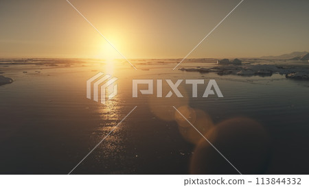 Antarctica sunset. Epic aerial view drone flight. Fastover the ocean water and glacier ice. Orange sun light given bright beams. Antarctica sunset. Epic aerial view drone flight. Fastover the ocean water and glacier ice. Orange sun light given bright beams. 113844332
