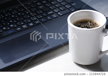 在辦公桌前用筆記型電腦一邊喝咖啡一邊工作的圖片 113844728