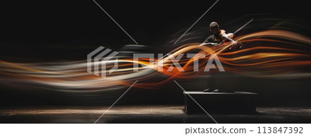 Violinist enveloped in dynamic light streams on a dark stage, illustrating musical passion 113847392