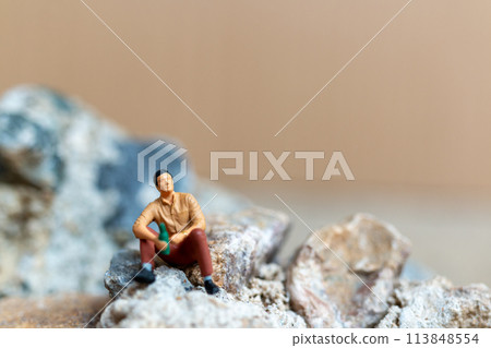 Miniature people , A young man sipping beer while sitting on the rock Miniature people , A young man sipping beer while sitting on the rock 113848554