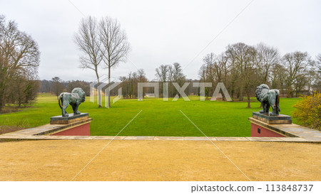 Overlooking a lush green lawn flanked by stone lion statues in Bad Muskau renowned park. Saxony, Germany Overlooking a lush green lawn flanked by stone lion statues in Bad Muskau renowned park. Saxony, Germany 113848737