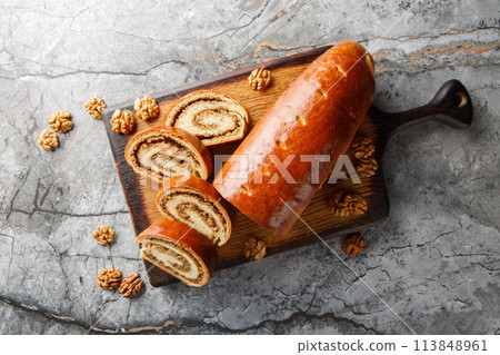 Eastern European Christmas and Easter nut roll made with ground walnuts closeup on the wooden board. Horizontal top view 113848961
