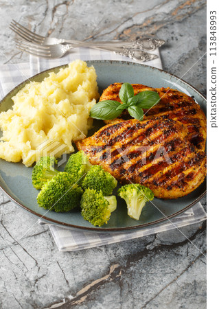 Grilled chicken breast served with mashed potatoes and broccoli close-up in a plate. Vertical 113848993