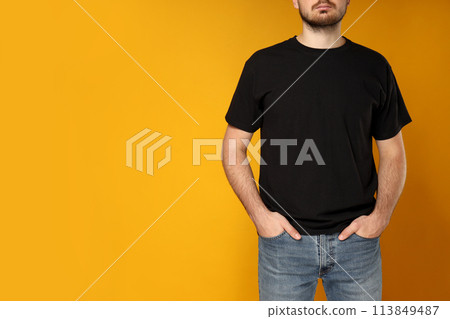 A young guy in a black T-shirt on a yellow background 113849487