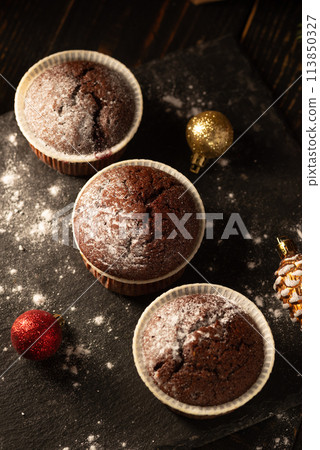 chocolate muffins with powdered sugar on top on a black background. Christmas decoration . Still life close up. Food photo. chocolate muffins with powdered sugar on top on a black background. Christmas decoration . Still life close up. Food photo. 113850327