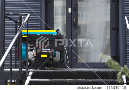 Portable electric generator running in the cold winter.Energy genocide. Power outage as a result of missile strikes by Russia on energy facilities of Ukraine. Small business use gasoline generators. 113850426