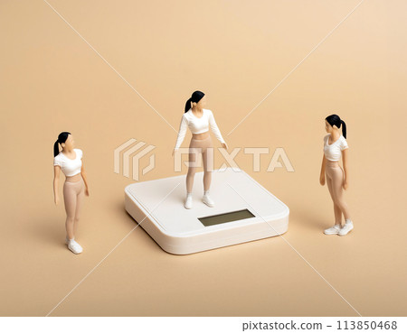 A group of sporty girls and a miniature model of a weight scale 113850468