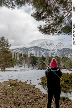 A woman in a pink hat admiring the mountains in the snowy landscape A woman in a pink hat admiring the mountains in the snowy landscape 113850848