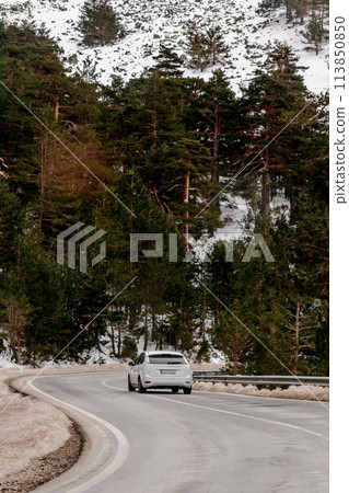 A white vehicle navigates a winding forest road on asphalt A white vehicle navigates a winding forest road on asphalt 113850850