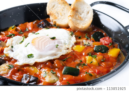 Vegetable pisto manchego with tomatoes, zucchini, peppers, onions,eggplant and egg, served in frying pan isolated on white background 113851925