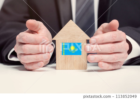 Businessman hand holding wooden home model with Kazakhstan flag. insurance and property concepts Businessman hand holding wooden home model with Kazakhstan flag. insurance and property concepts 113852049