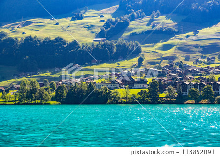 Swiss village Lungern with traditional houses, old church Alter Kirchturm along lovely emerald green lake Lungerersee, canton of Obwalden Switzerland Swiss village Lungern with traditional houses, old church Alter Kirchturm along lovely emerald green lake Lungerersee, canton of Obwalden Switzerland 113852091