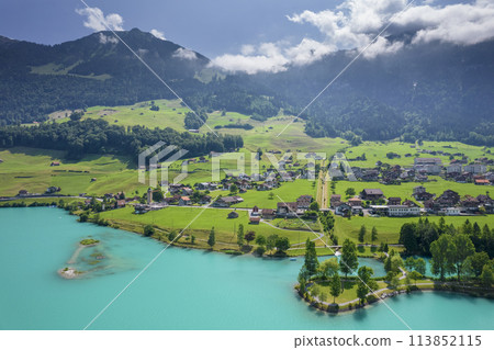 Aerial of Swiss village Lungern with traditional houses, old church Alter Kirchturm along lovely emerald green lake Lungerersee, canton of Obwalden Switzerland 113852115