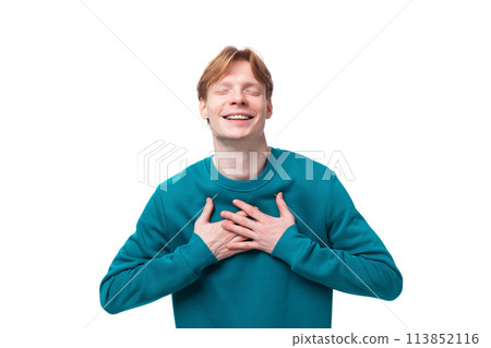 a young guy with red hair dressed in a blue pullover feels joy with his eyes closed 113852116