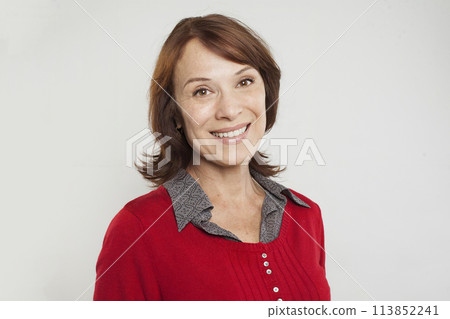 Cute casual mature woman with brown hair and cute smile looking at camera on white background 113852241