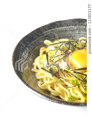 Hot oil soba noodles topped with egg yolk, shredded seaweed, and green onions photographed against a white background 113853177