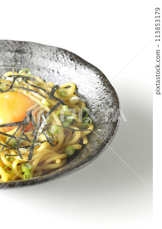 Hot oil soba noodles topped with egg yolk, shredded seaweed, and green onions photographed against a white background 113853179