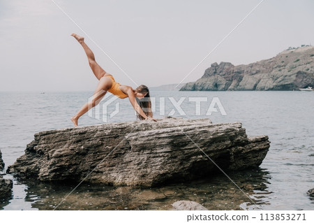 Woman sea yoga. Back view of free calm bliss satisfied woman with long hair standing on top rock with yoga position against of sky by the sea. Healthy lifestyle outdoors in nature, fitness concept. Woman sea yoga. Back view of free calm bliss satisfied woman with long hair standing on top rock with yoga position against of sky by the sea. Healthy lifestyle outdoors in nature, fitness concept. 113853271