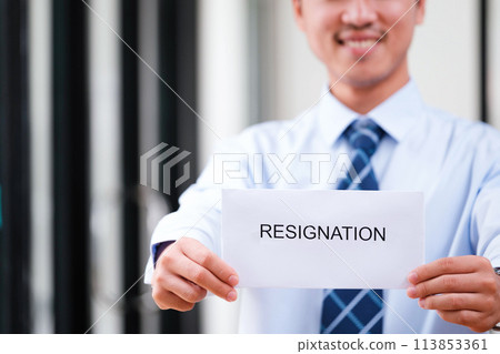 Smiling man displays resignation letter, suggesting a hopeful new beginning. 113853361